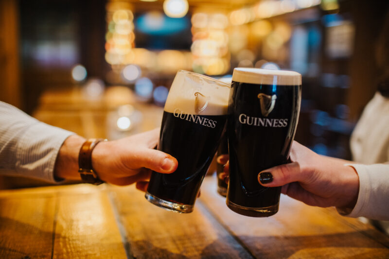 Pints of Guinness clinking together in a joyful cheer at The Hercules Holloway, creating a perfect moment of camaraderie.
